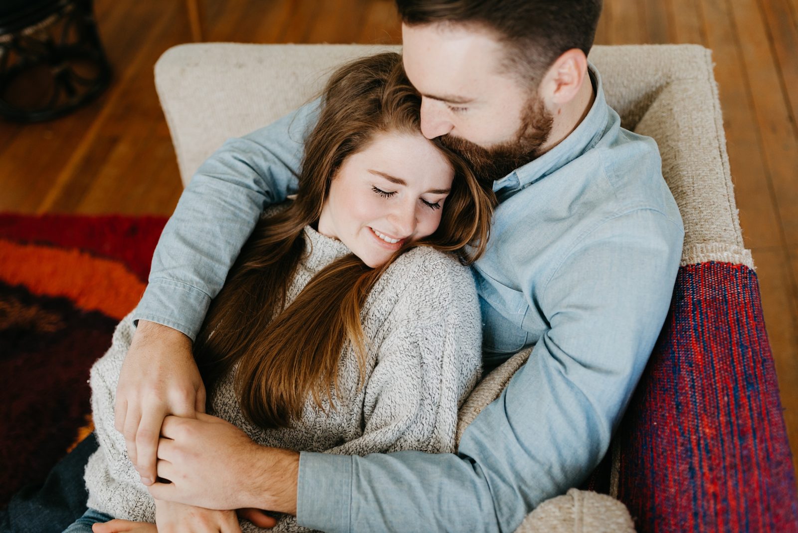 Cuddling couple on couch during in home engagement session