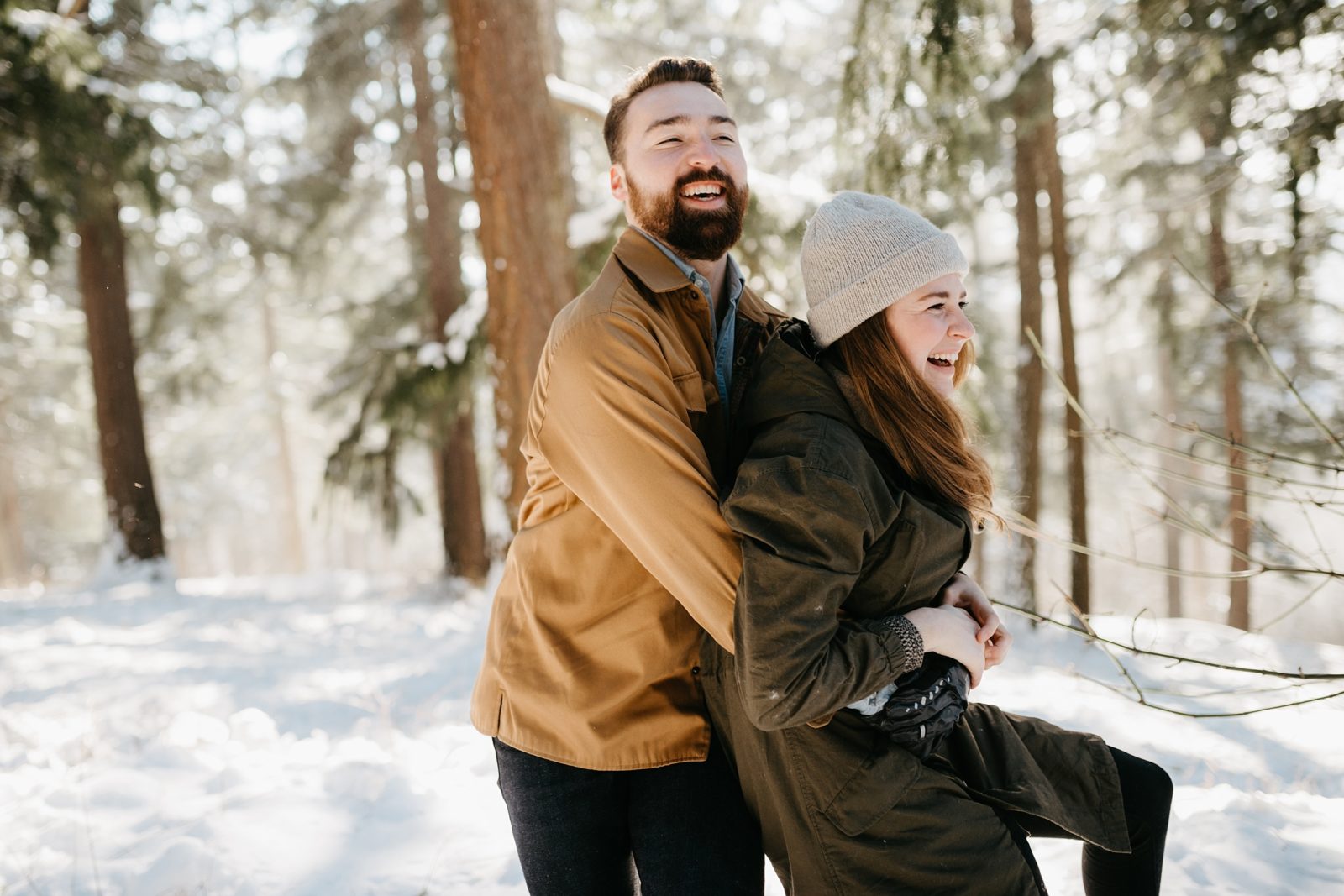 Fun couple playing in the snow during a winter engagement session