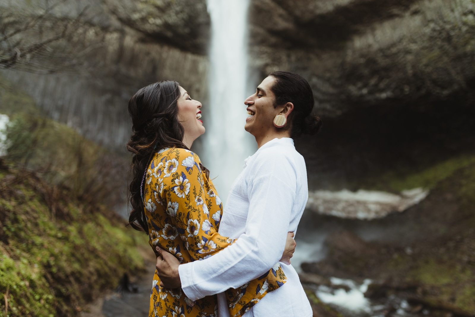 Cool couple laughing in front of waterfall during engagement photos in the Columbia River Gorge