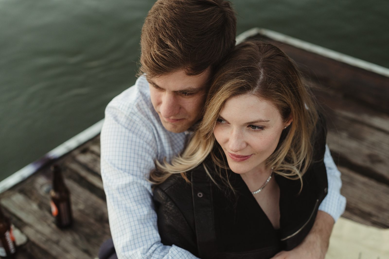Stylish couple sitting on dock at Portland waterfront during their engagement session.