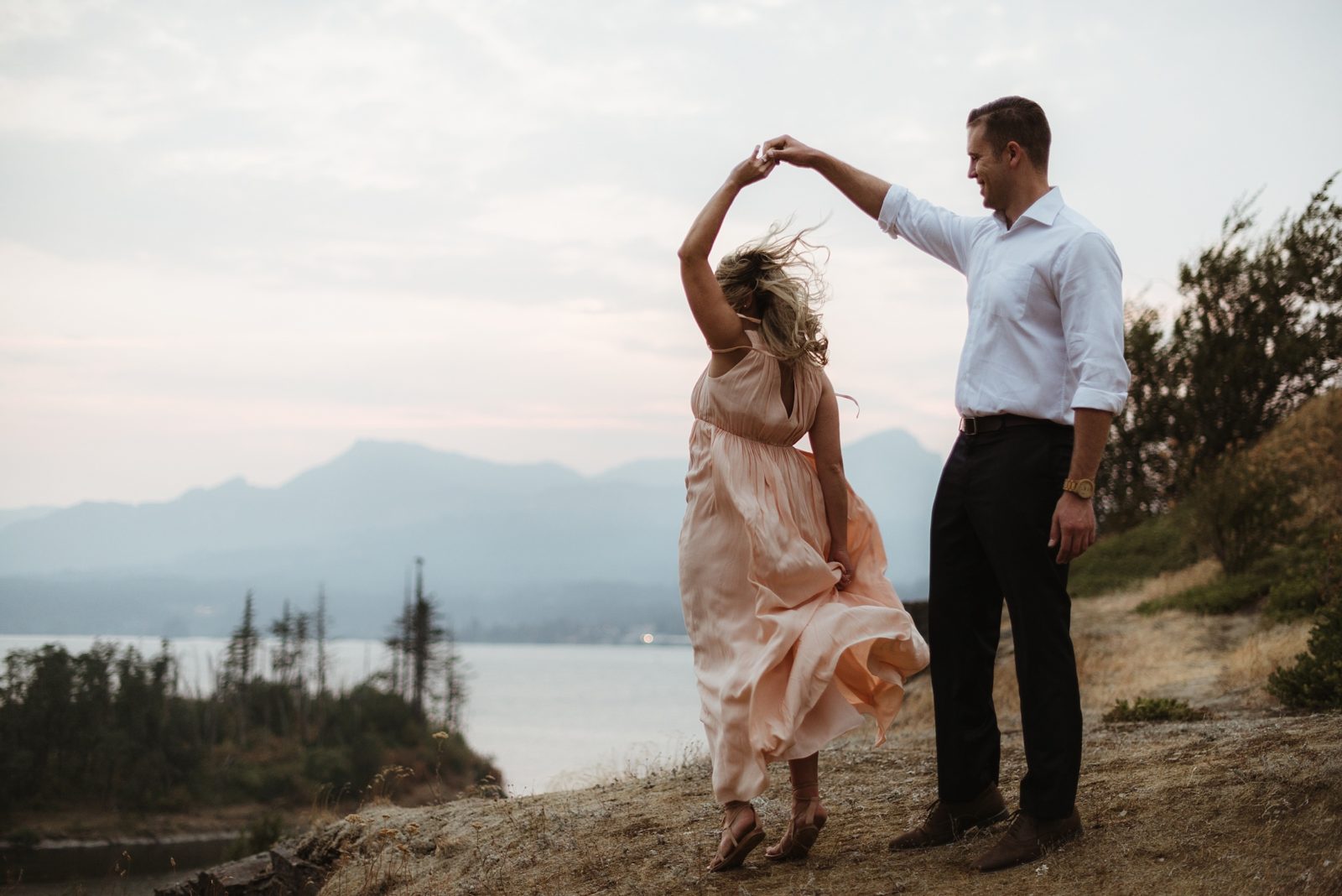 Couple dancing on cliffside during engagement photos in the Columbia River Gorge at sunset