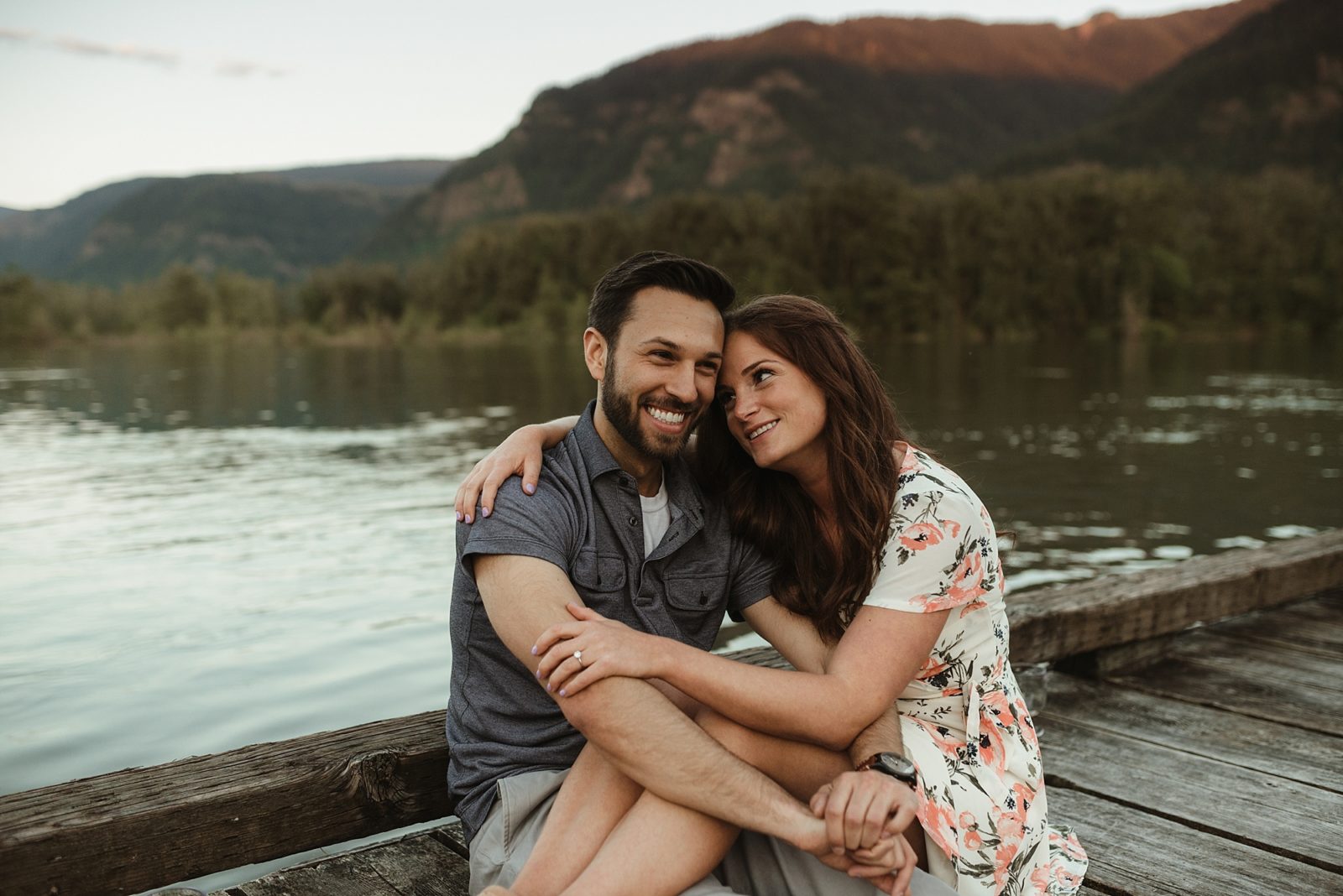 Adorable couple sitting on dock in the Columbia River during a sunset engagement session
