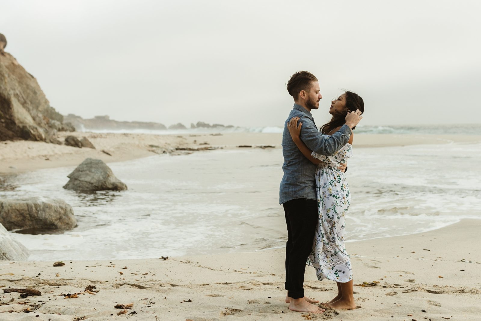 Gorgeous mixed race couple embracing romantically on a beach in Big Sur, California.