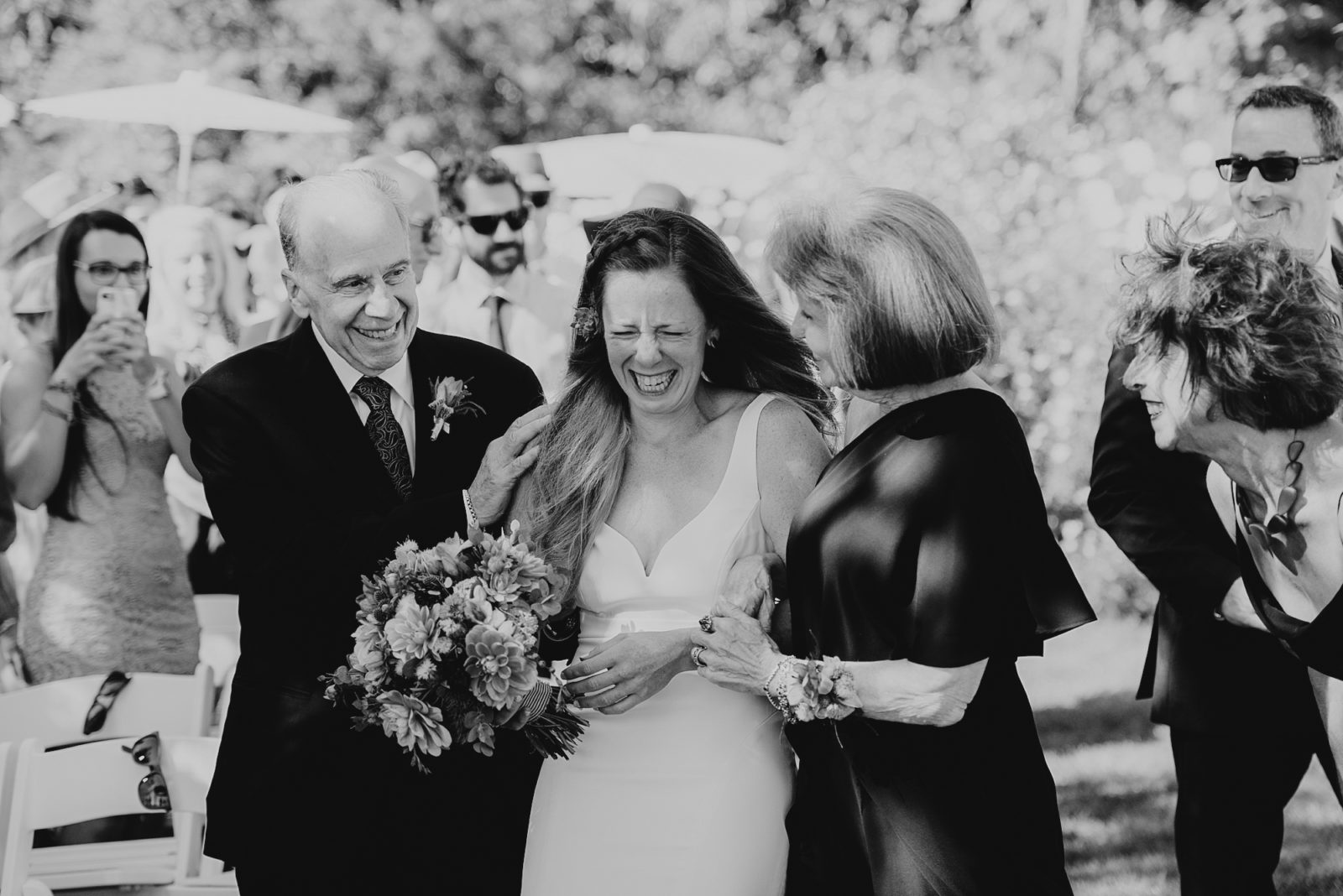 Bride crying as she walks down the aisle with both her parents during the wedding ceremony at Husum Highlands