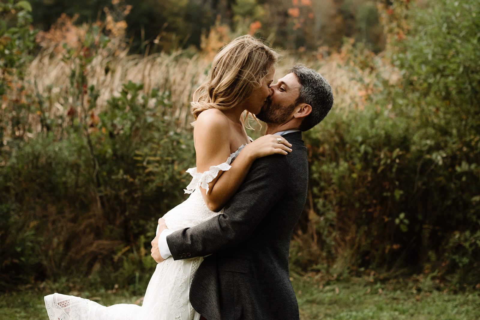 New England bride and groom embracing in front of Fall foliage